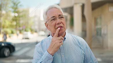 Senior man standing with doubt expression at street