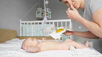 Father changes dirty diaper and holds breath closing nose