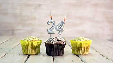 Happy birthday muffins with candles with the number 24. Card copy space with pies for congratulations.