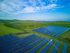Solar panels to generate energy from the sun's rays are installed in the meadows under a blue sky with sun