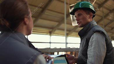 Livestock workers talking cowshed discussing diagram. Agribusiness team at work.