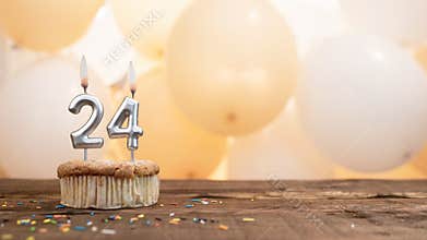 Happy birthday card with candle number 24 in a cupcake against the background of balloons. Copy space happy birthday for twenty