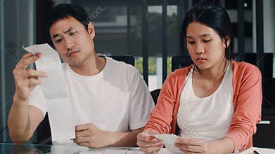 Young Asian Pregnant couple records of income and expenses at home. Dad worried, serious, stress while record budget, tax,