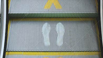 Escalators in shopping center with symbols of social distancing.