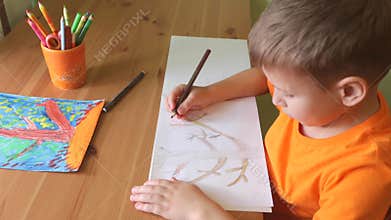 Boy drawing tree sitting by desk