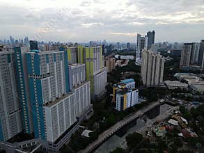 Aerial drone view of modern apartment building in Jakarta central business district with Jakarta cityscape and noise cloud.