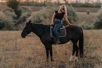 Pretty woman sitting on horse on nature background. Concept of love, friendship, farm animals