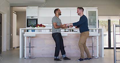 Multi ethnic gay male couple dancing in kitchen