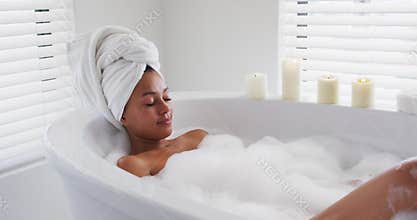 African american woman relaxing in the bath tub in the bathroom at home
