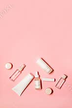 Vertical flat lay shot with a copy space on a pink background with skincare goods: hand cream, deodorant, lipstick, serum,
