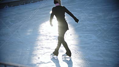 Ice skating - young woman figure skating on the public ice rink in the morning