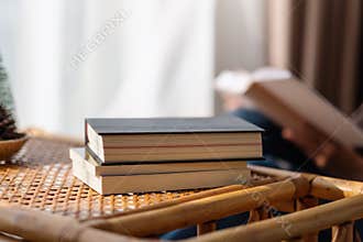 Books on wooden table with blurred of woman reading book in background