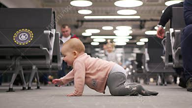 Little baby girl crawling in the airport lounge.