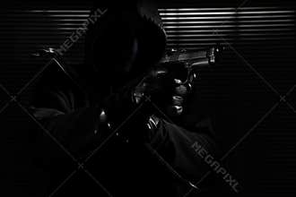 Burglary and robbery. skillful professional masked burglar holding a gun and crowbar and breaking into the house, hand close up on
