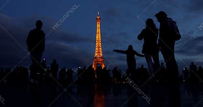 People and tourists walk on the Palais de Chaillot esplanade after sunset to photograph the Eifell tower.