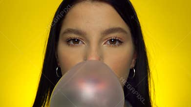 Woman blowing big bubble gum ball and laughing, happy female portrait