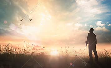 Silhouette of Person Standing in Field Watching Bright Sunrise Sky