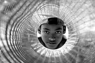 The dark eyes. Portrait of a little boy looking into the cage.