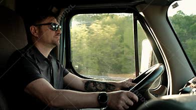 Truck driver rides to destination cargo . Man driving truck at road on warm summer day. Slow motion Close up