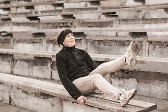 Retired woman doing abdominal exercises in an abandoned stadium.