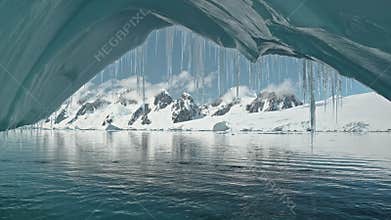 Closeup iceberg arch at turquoise ocean bay with mountains on snow aerial. Environment preserve