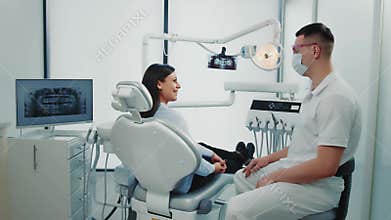A male dentist communicates with a female patient in a dental office. Dental health concept.