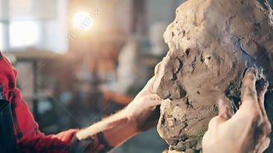 Clay sculpture is getting molded by a male artist