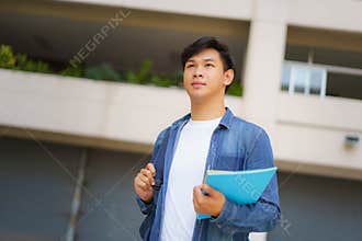 Portrait of a Asian college man student carrying a backpack and standing in a school hallway at campus