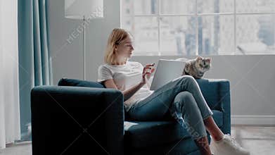 Tranquil woman uses tablet near purebred cat on couch