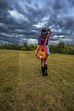 Beautiful brunette is walking in the middle of a storm with her guitar.