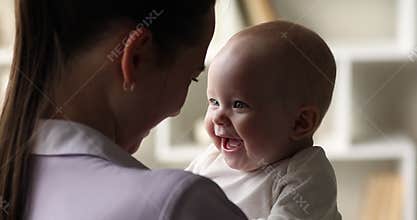 Loving mother holding cheerful carefree newborn adorable baby