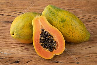 Papayas with half fruit over wooden table