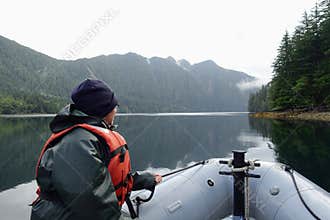A woman at the front of a zodiac on a tour exploring the ocean, coastlines, forest and islands of Gwaii Haanas, Haida Gwaii