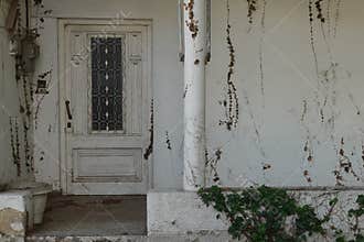 Old house porch with vintage door and withered plants