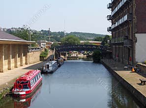 The canal and entrance to brighouse basin in west yorkshire with traditional narrow boats and buildings