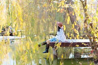 Autumn lake woman. She sits by a pond on a wooden pier in autumn and admires nature. The concept of tourism, weekends