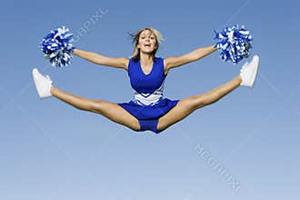 Cheerleader With Pompoms Doing Splits Against Sky