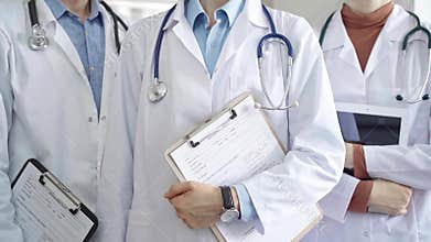 Group of doctors wearing white coats and stethoscopes standing with clipboards. Medical team at work