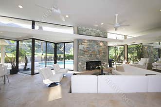 Seating Area And Stone Fireplace In Spacious Living Room With Pool View