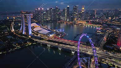 Real time aerial video of Sunset in Singapore City Skyline. Flying Towards Marina Bay Sands and Gardens In Singapore