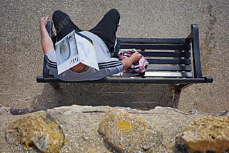 Man protecting his head from the summer sun with a magazine,