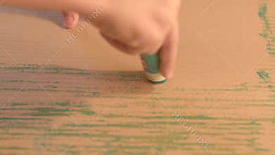 Engaging in a Creative Drawing Process on Brown Paper Utilizing a Bright Green Crayon