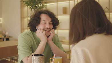 A young couple eats, drinks coffee and talks in a very beautiful cafe. A guy and a girl are in a very good mood