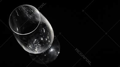Beer pours in glass on black. High angle shot.