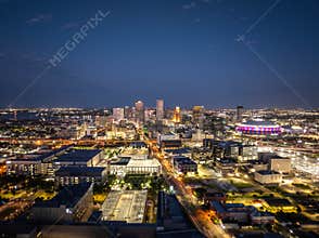 Glowing New Orleans city skyline at dusk with illuminated buildings, busy streets, and the Caesars Superdome, creating a