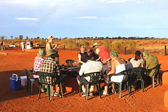 Tourists have a picknick along Uluru Ayers Rock in the red desert, Australia