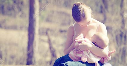 Mother feeding her baby in nature outdoors in the park