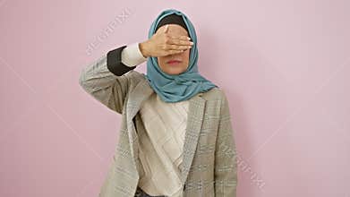 Mature, serious hispanic woman in hijab, blindly covering eyes with hand - a sad reflection of rejection, hiding behind her veil