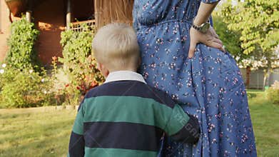 Little boy hearing his pregnant mom's belly outdoor