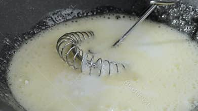The cook adds milk to beaten egg with sugar. Preparation of sweet food.